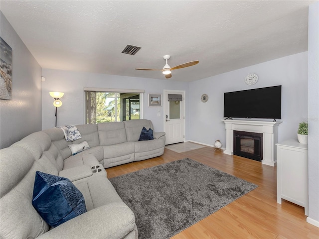 living room with ceiling fan, wood-type flooring, and a textured ceiling