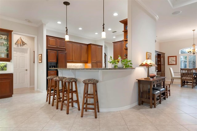 kitchen featuring crown molding, hanging light fixtures, kitchen peninsula, a breakfast bar, and stone countertops