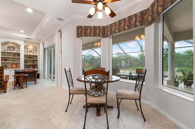 tiled dining space featuring ceiling fan, built in features, crown molding, and a raised ceiling