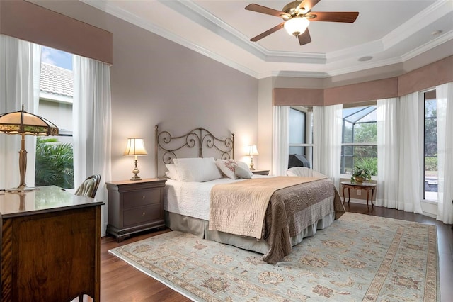 bedroom with ceiling fan, multiple windows, dark hardwood / wood-style flooring, and a raised ceiling