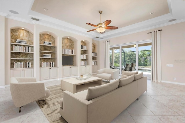 living room featuring built in shelves, ornamental molding, and a raised ceiling