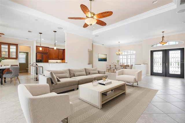 living room with light tile patterned floors, ceiling fan with notable chandelier, a raised ceiling, french doors, and crown molding