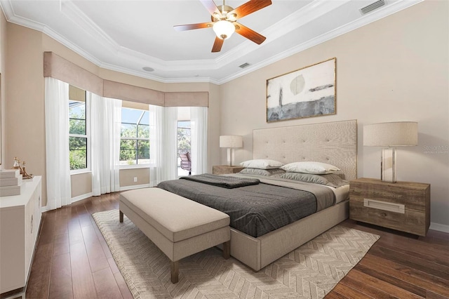 bedroom with crown molding, a raised ceiling, visible vents, and hardwood / wood-style flooring