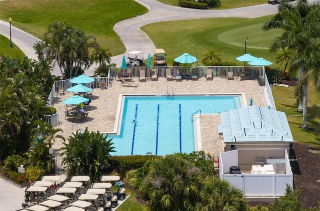 community pool with fence, a yard, a patio area, and view of golf course