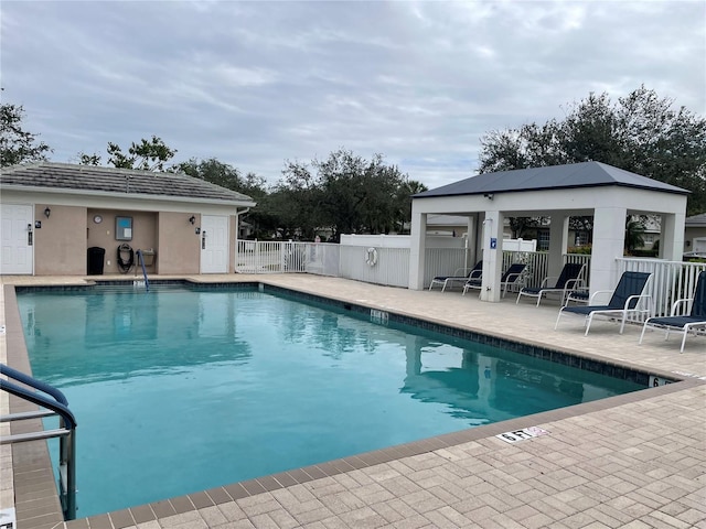 community pool with fence, a gazebo, and a patio