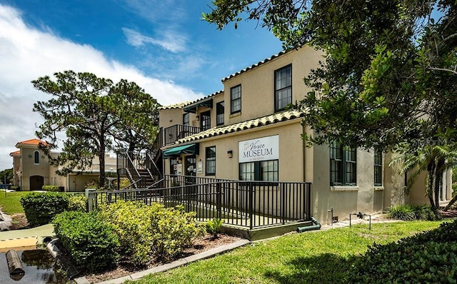 view of front facade with a tiled roof, a front lawn, and stucco siding