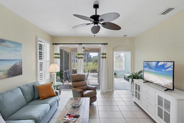 living room featuring ceiling fan, light tile patterned floors, and a textured ceiling