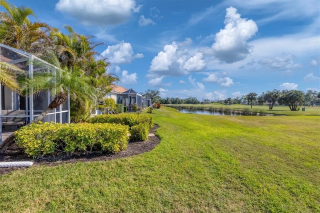 view of yard with a lanai and a water view