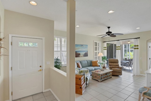 tiled entryway with ceiling fan, a healthy amount of sunlight, and a textured ceiling