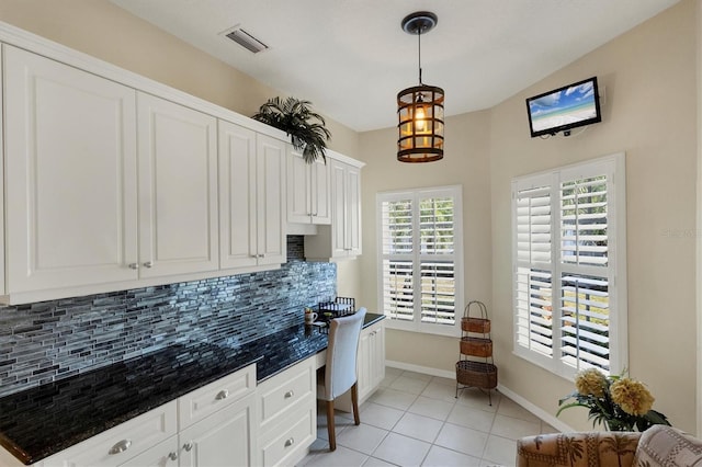 kitchen with built in desk, light tile patterned floors, tasteful backsplash, and white cabinetry