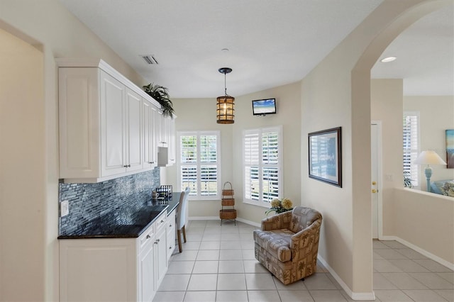 bar with decorative light fixtures, backsplash, white cabinetry, and light tile patterned flooring