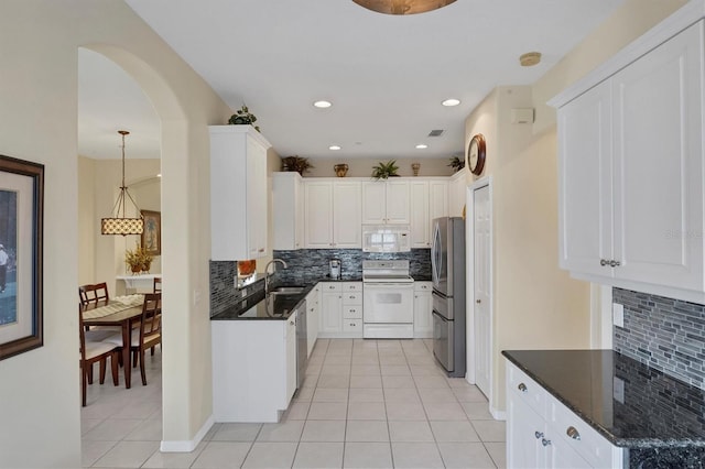 kitchen featuring white appliances, white cabinetry, dark stone countertops, sink, and light tile patterned floors