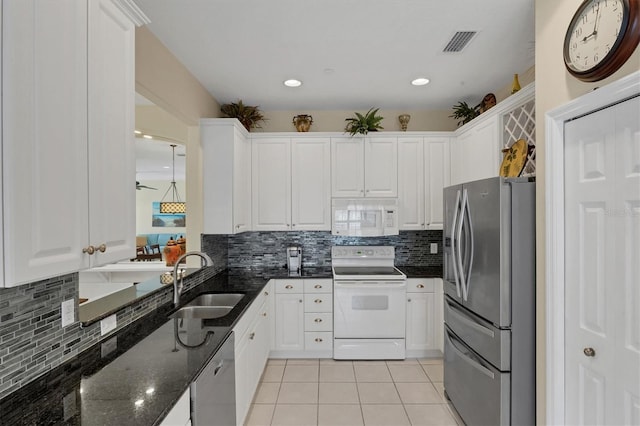 kitchen featuring light tile patterned floors, stainless steel appliances, dark stone countertops, white cabinets, and sink