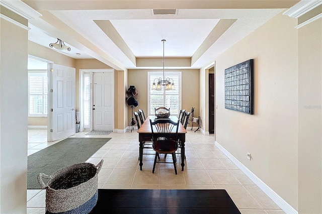 dining area featuring an inviting chandelier, light tile patterned flooring, and a tray ceiling