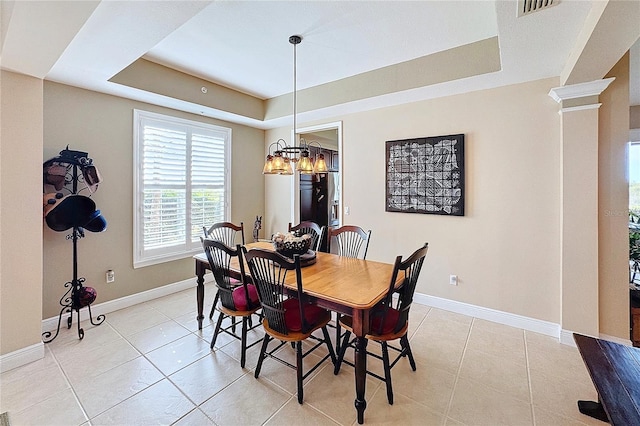 tiled dining area with ornate columns, a chandelier, and a tray ceiling