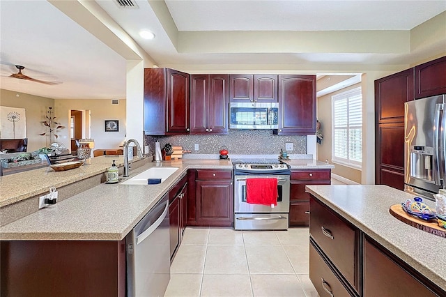 kitchen featuring ceiling fan, a raised ceiling, sink, stainless steel appliances, and light tile patterned floors