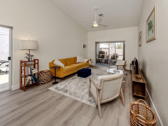 living room featuring light hardwood / wood-style floors, vaulted ceiling, and ceiling fan