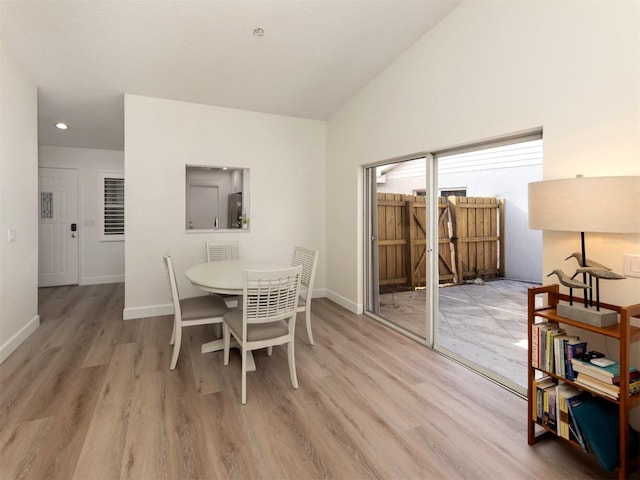 dining space with light wood-type flooring and lofted ceiling