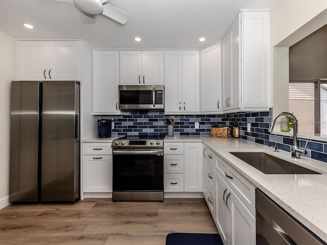 kitchen featuring sink, white cabinets, light stone countertops, light hardwood / wood-style floors, and stainless steel appliances