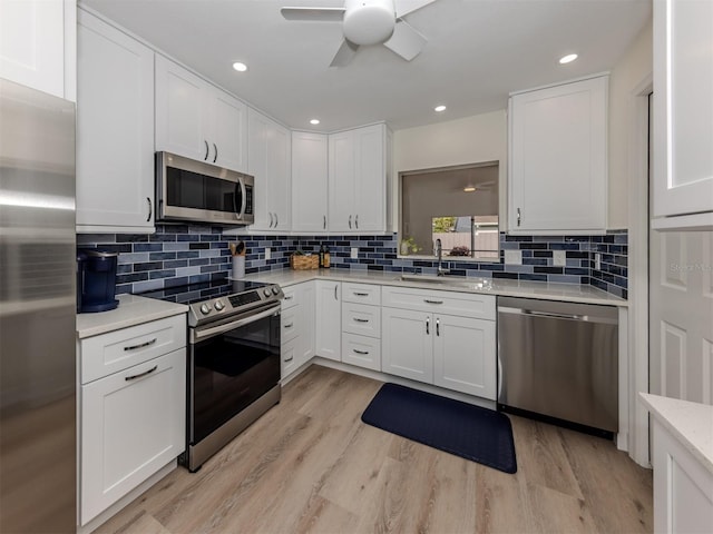 kitchen with light hardwood / wood-style floors, sink, white cabinetry, and stainless steel appliances