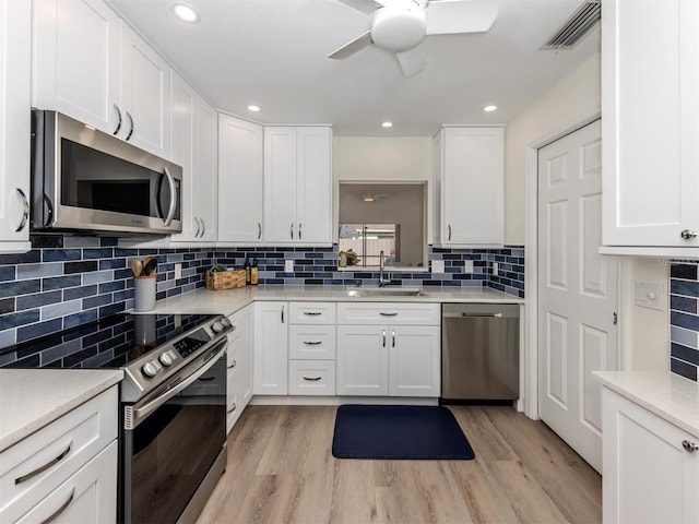 kitchen with sink, white cabinetry, light hardwood / wood-style flooring, and appliances with stainless steel finishes