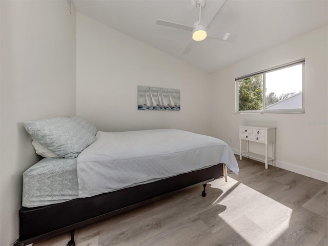 bedroom with light hardwood / wood-style flooring, vaulted ceiling, and ceiling fan