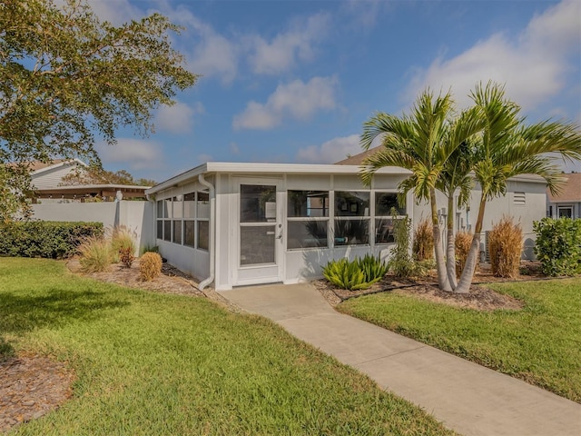 back of property with a sunroom and a lawn