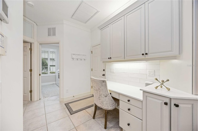 home office with light tile patterned flooring, ornamental molding, and built in desk