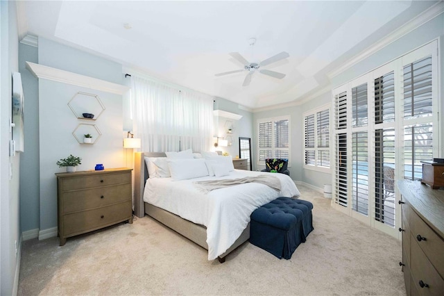 bedroom featuring ceiling fan, a tray ceiling, and light carpet