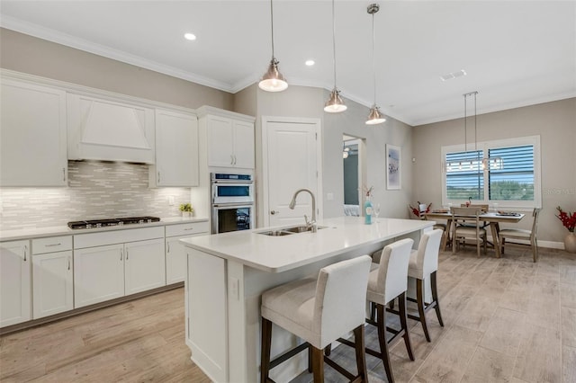 kitchen featuring sink, white cabinetry, and a center island with sink