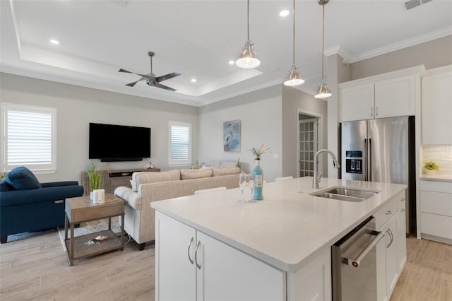 kitchen with a center island with sink, white cabinetry, and a tray ceiling