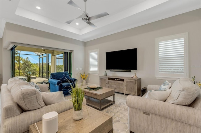 living room with ceiling fan and a raised ceiling