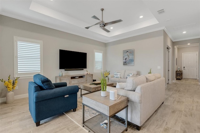 living room with ceiling fan, ornamental molding, and a tray ceiling