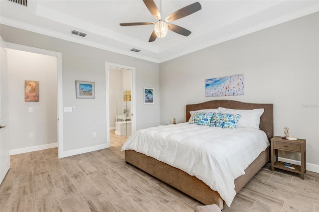 bedroom featuring crown molding, ceiling fan, a tray ceiling, light hardwood / wood-style floors, and connected bathroom