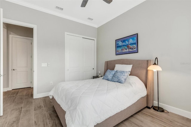 bedroom with ceiling fan, light hardwood / wood-style floors, a closet, and crown molding