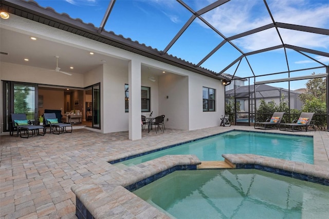 view of swimming pool with ceiling fan, an in ground hot tub, glass enclosure, and a patio