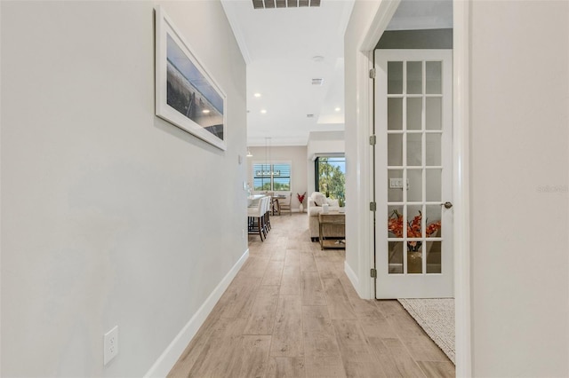 hall featuring light wood-type flooring and crown molding