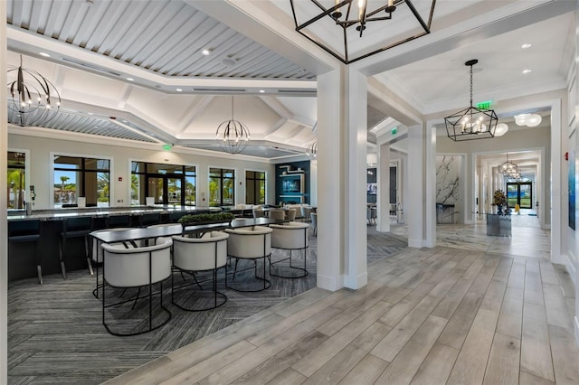 interior space with vaulted ceiling, french doors, ornamental molding, an inviting chandelier, and a breakfast bar area