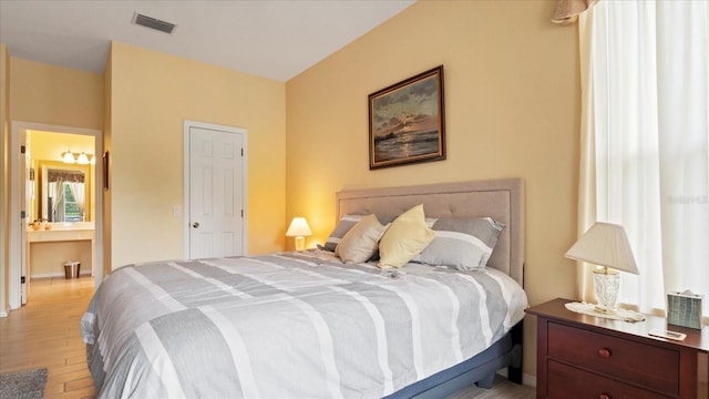 bedroom with connected bathroom and light hardwood / wood-style floors