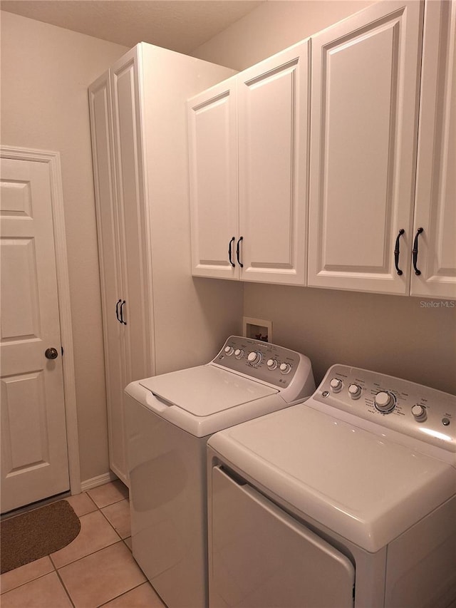 laundry area with light tile patterned flooring, cabinets, and washing machine and dryer