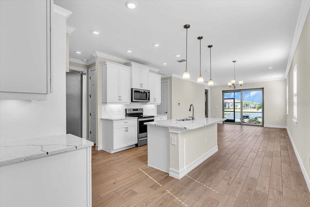 kitchen featuring an island with sink, appliances with stainless steel finishes, pendant lighting, white cabinets, and sink