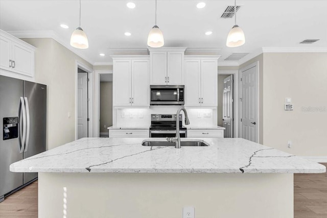 kitchen with hanging light fixtures, appliances with stainless steel finishes, and a center island with sink