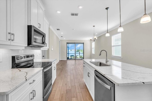 kitchen with sink, appliances with stainless steel finishes, an island with sink, and white cabinetry