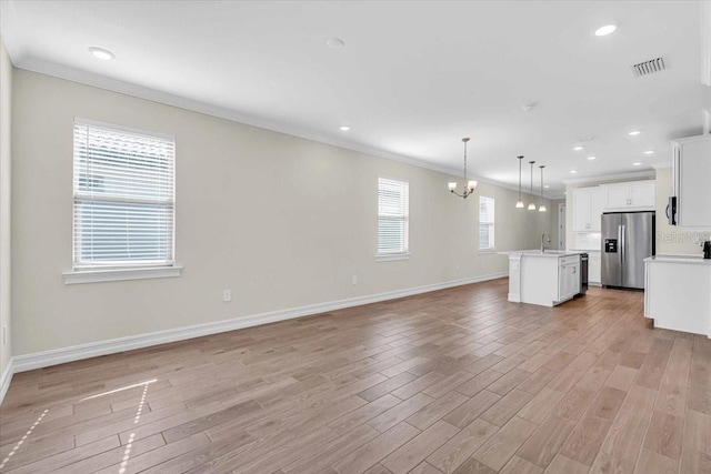 unfurnished living room with a wealth of natural light, sink, and crown molding