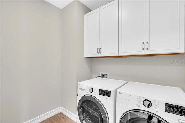 laundry area featuring hardwood / wood-style flooring, separate washer and dryer, and cabinets