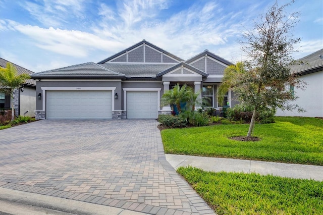 view of front facade with a garage, stone siding, decorative driveway, and a front yard