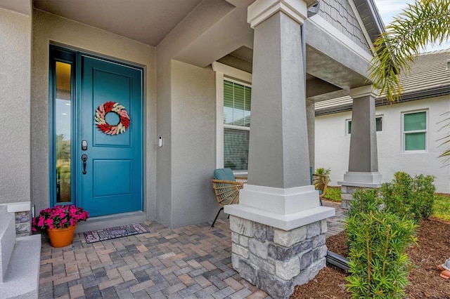 property entrance with a porch and stucco siding