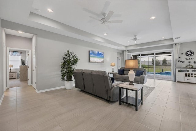 living area with light tile patterned floors, a tray ceiling, recessed lighting, and baseboards