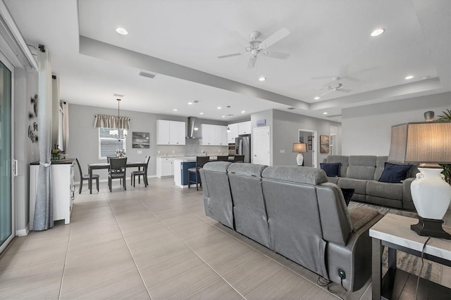 living area with recessed lighting, a raised ceiling, visible vents, and ceiling fan