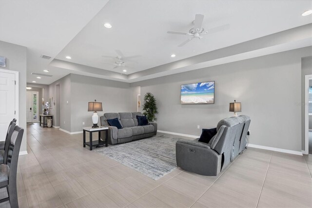 living area with recessed lighting, a tray ceiling, visible vents, and baseboards